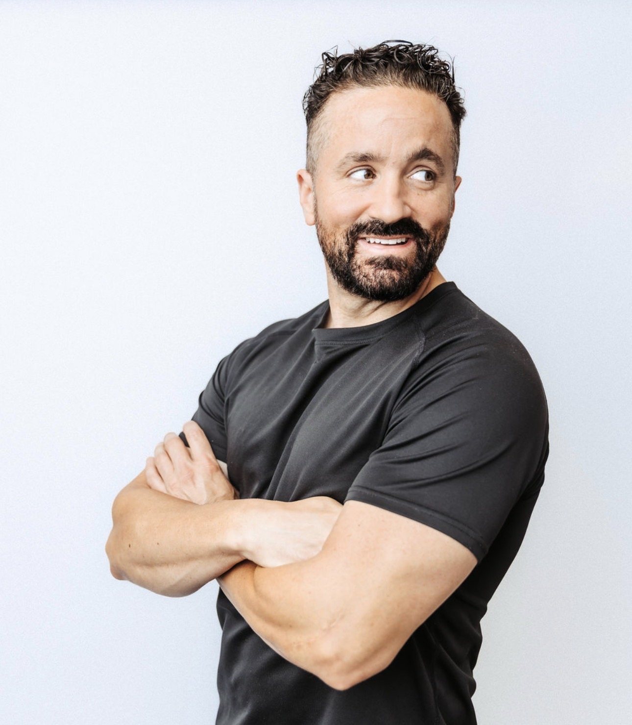 Studio portrait of Shawn Taylor with arms crossed, smiling and looking to the side